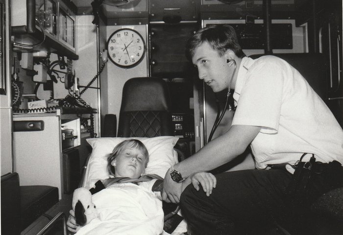 Jeff Bourke, as a young EMT, comforting a young patient in the back of an ambulance